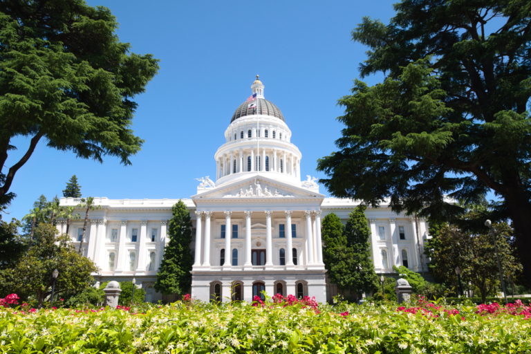 California State Capitol in Sacramento framed by trees and flowers in May 2024