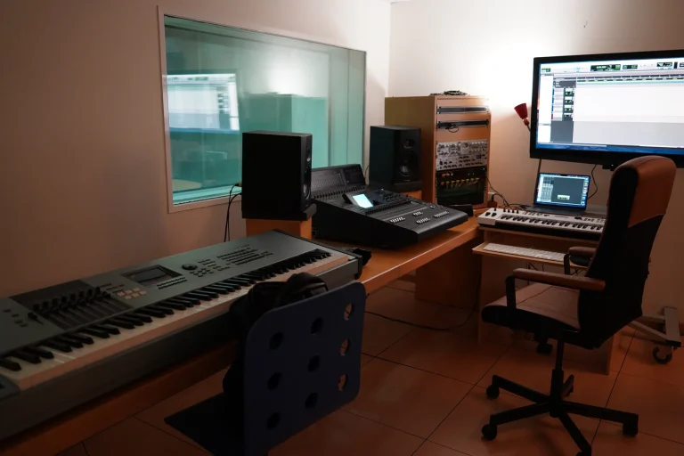 Electronic keyboards, a mixing console, speakers and computer screens inside a music production studio