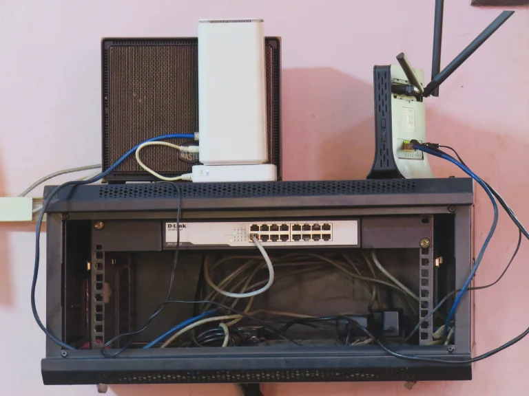 Wall-mounted network rack holding an Ethernet switch, routers and connected cables