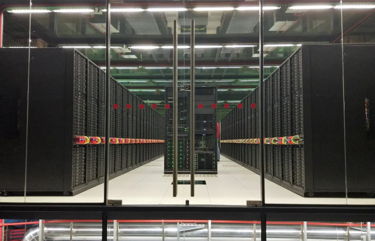 Rows of black server racks with colorful cables behind glass doors at Barcelona Supercomputing Center