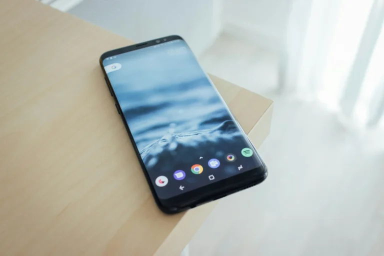 A smartphone rests on the corner of a wooden table