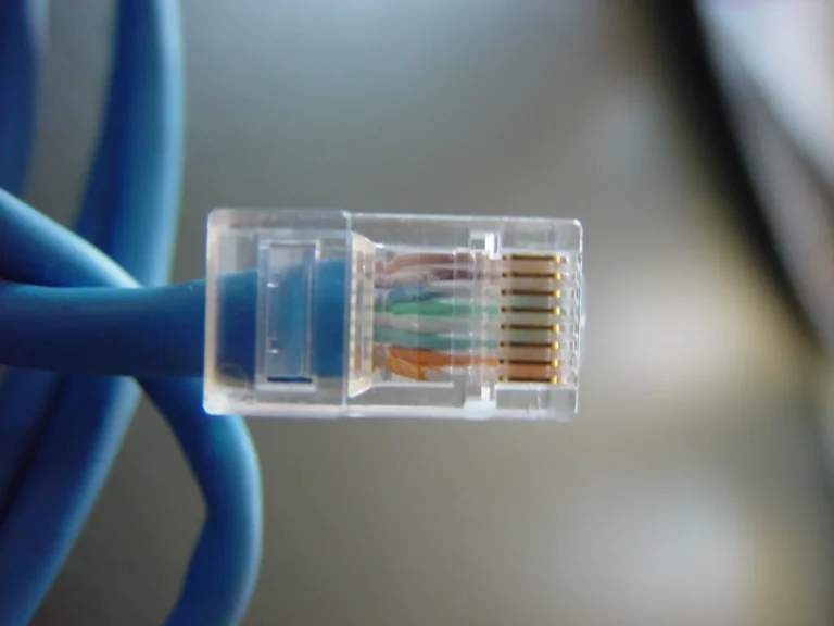Transparent connector on a blue network cable with colored wires visible inside