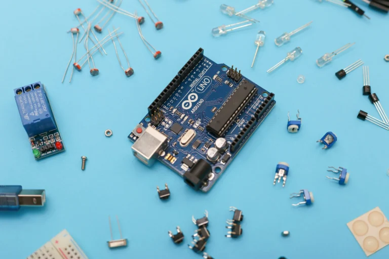 An Arduino Uno board and separate electronic components on a blue surface