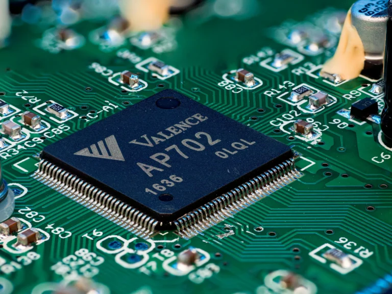 A dark Valence processor with metal pins sits on a green circuit board