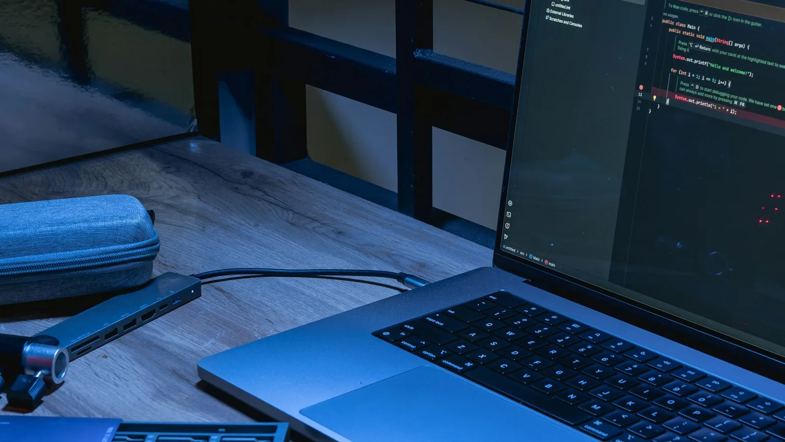 Laptop displaying code on a wooden desk under blue light