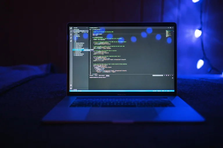 Programming code fills a laptop screen against blue lighting