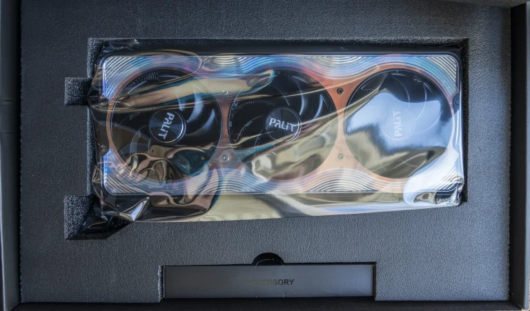 A Palit GeForce RTX 5090 GameRock graphics card with three cooling fans inside protective packaging
