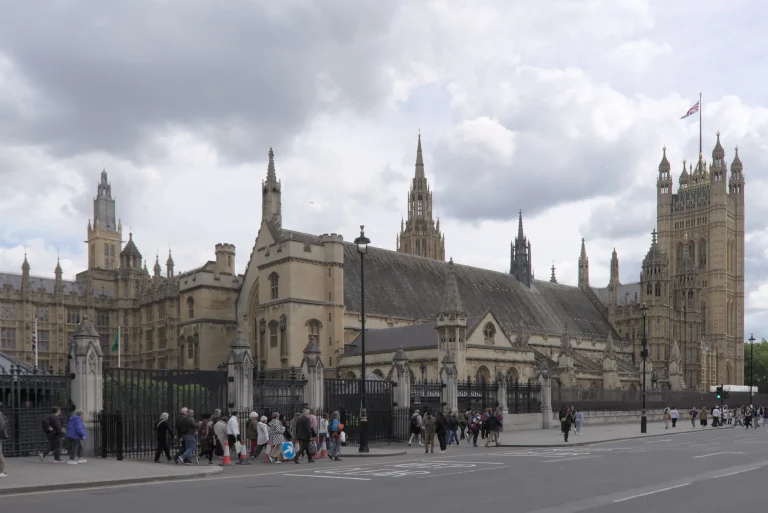 West facade of the Palace of Westminster with pedestrians on the pavement