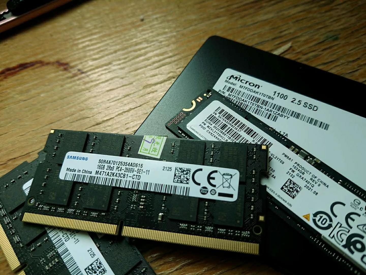 Laptop RAM modules beside a Samsung NVMe SSD and a Micron SSD on a wooden surface