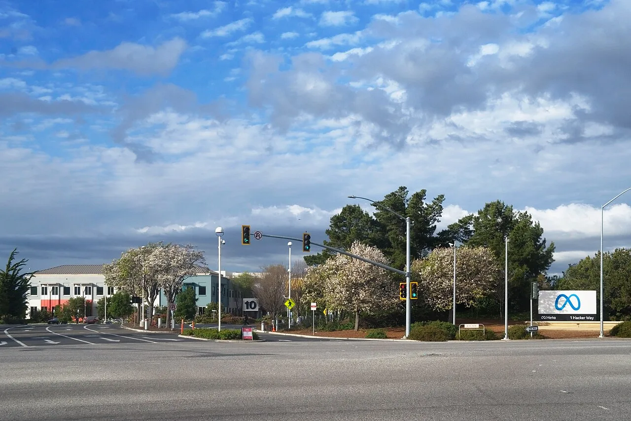 Meta headquarters entrance in Menlo Park with the blue Meta sign beside trees and office buildings