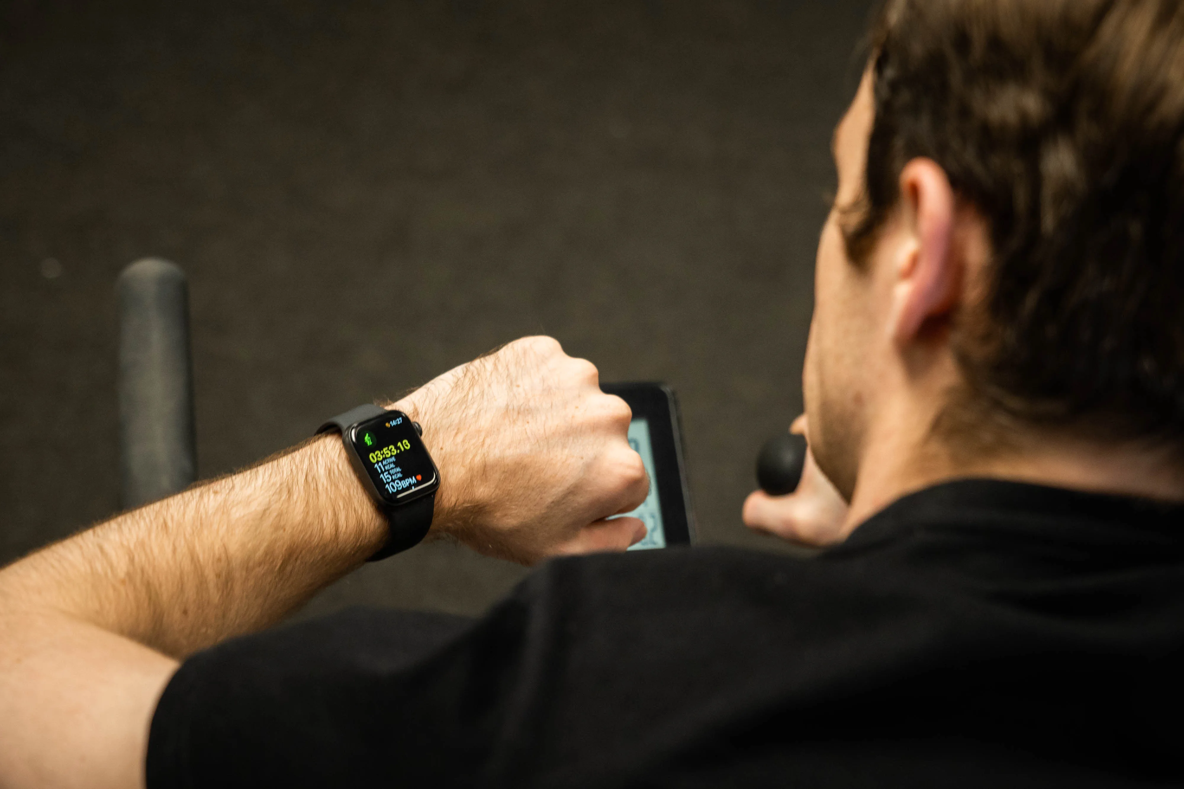 Contextual photo from July 2021 of a cyclist checking a smartwatch during an indoor workout