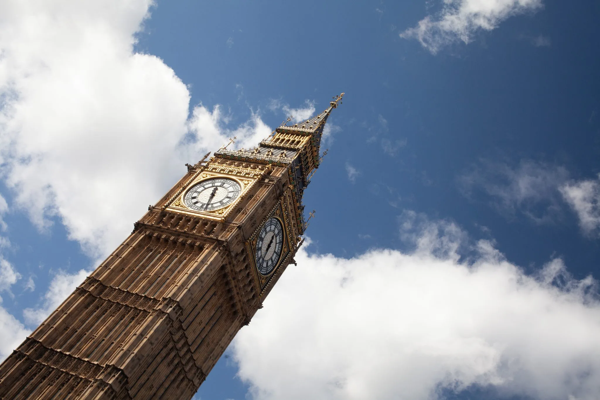 Elizabeth Tower and its clock faces seen from below against a blue sky