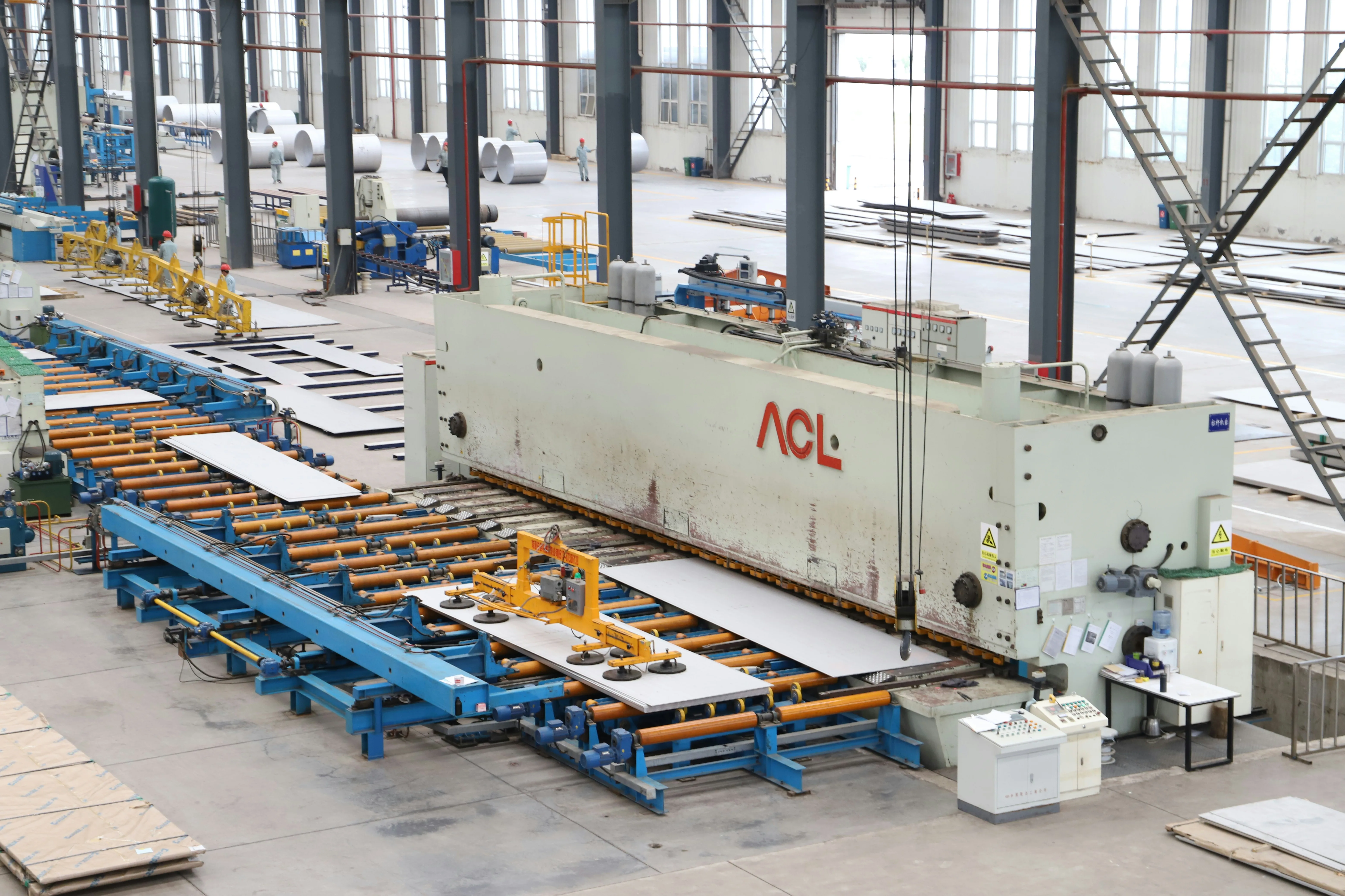 Large metalworking machine and roller conveyors carry metal sheets across a bright factory floor