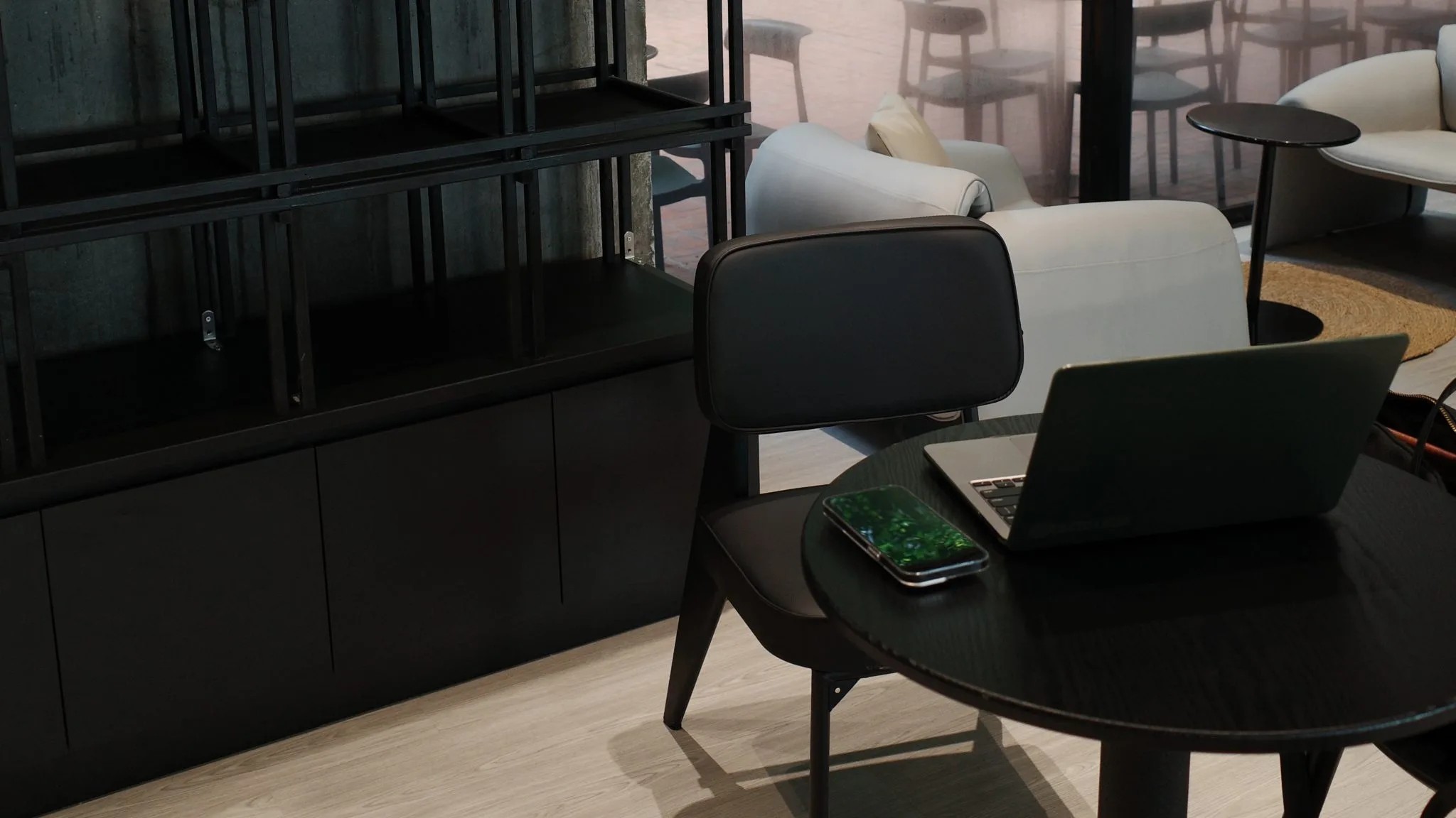 Laptop on a black table beside an empty chair