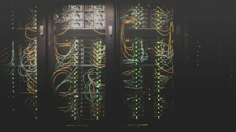 Orange and blue network cables and green lights behind black mesh doors in server racks
