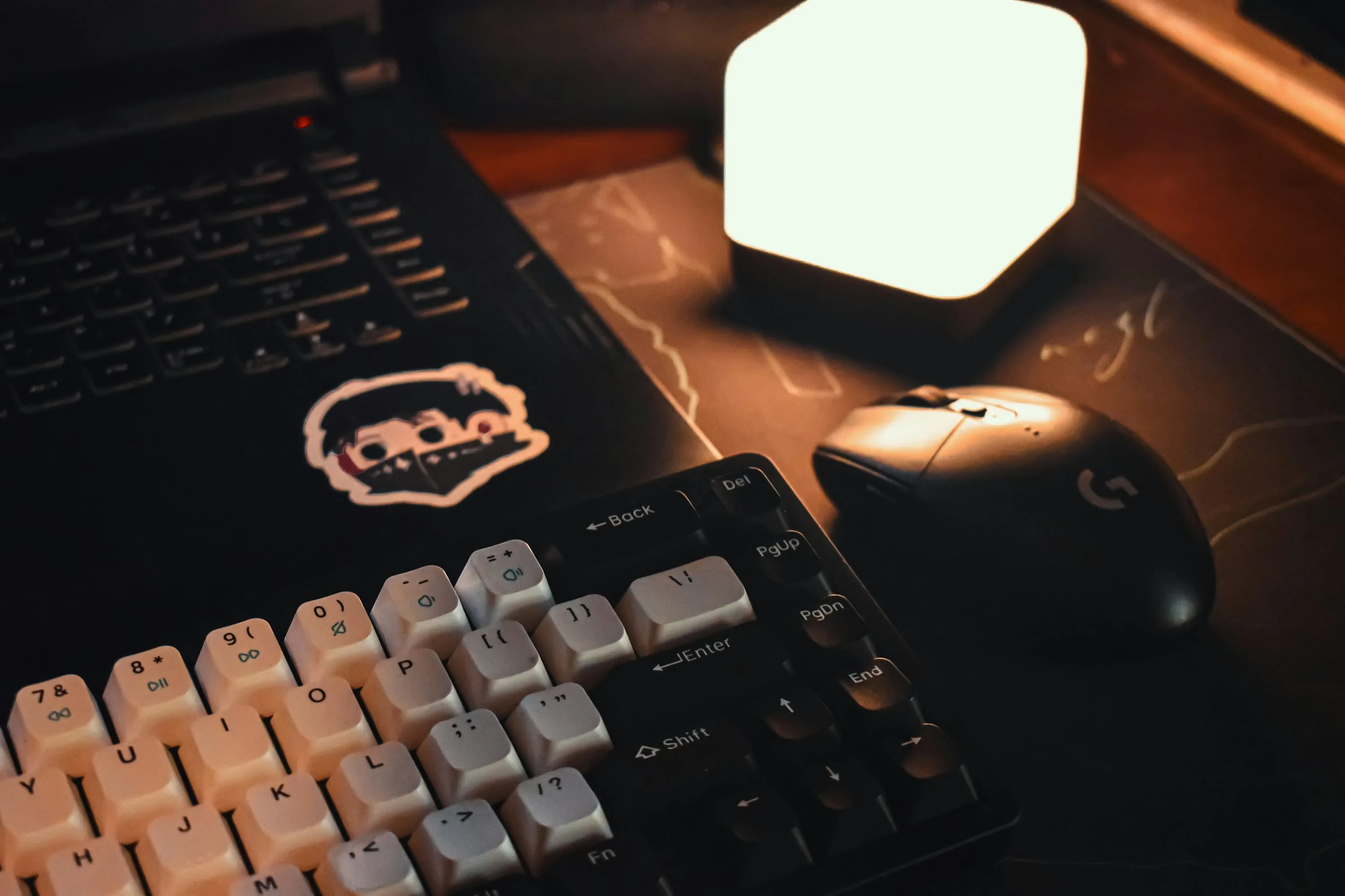 A mechanical keyboard and gaming mouse sit beside a glowing desk light