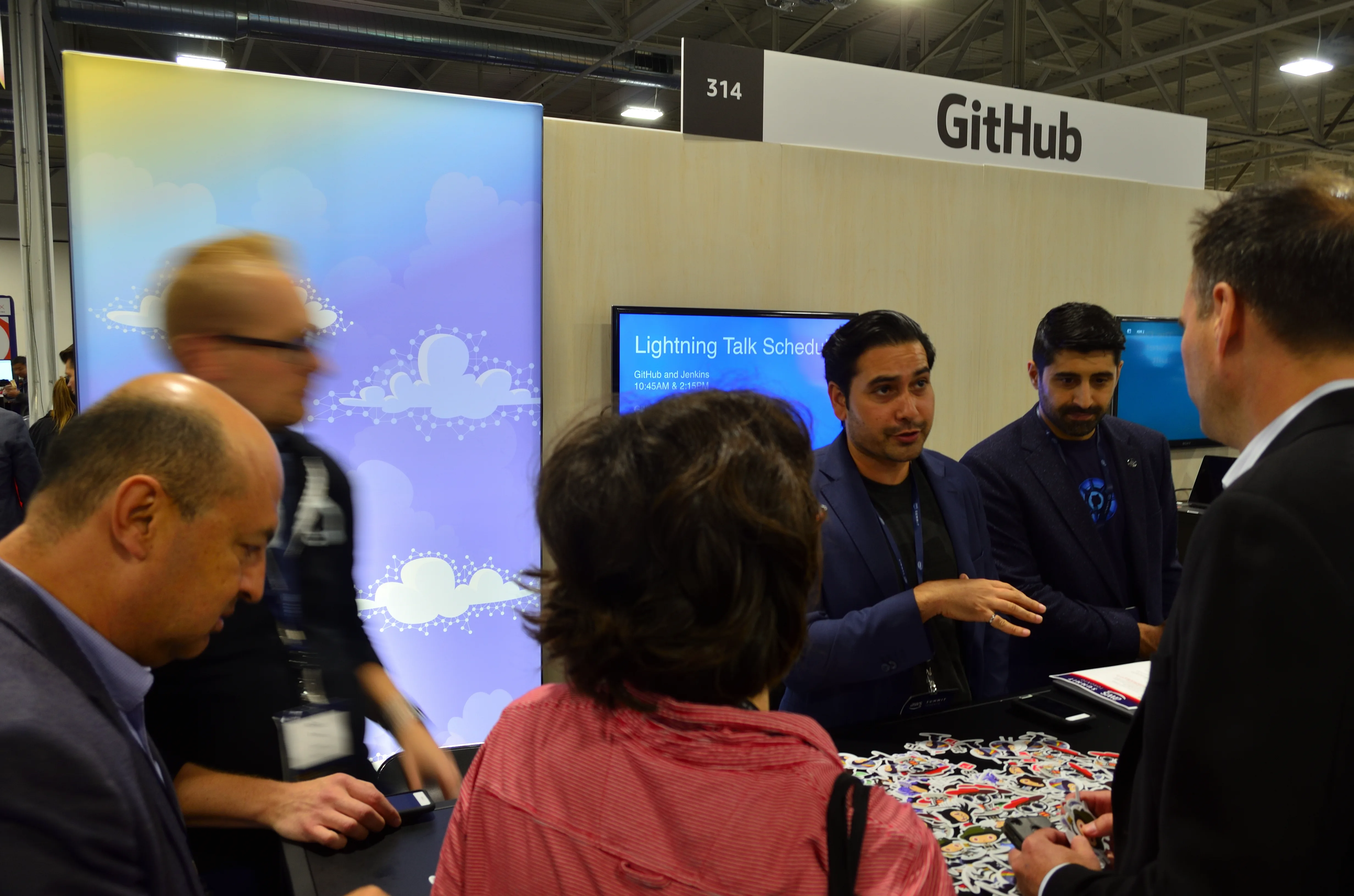 Visitors gathered at a GitHub exhibition booth with a large GitHub sign
