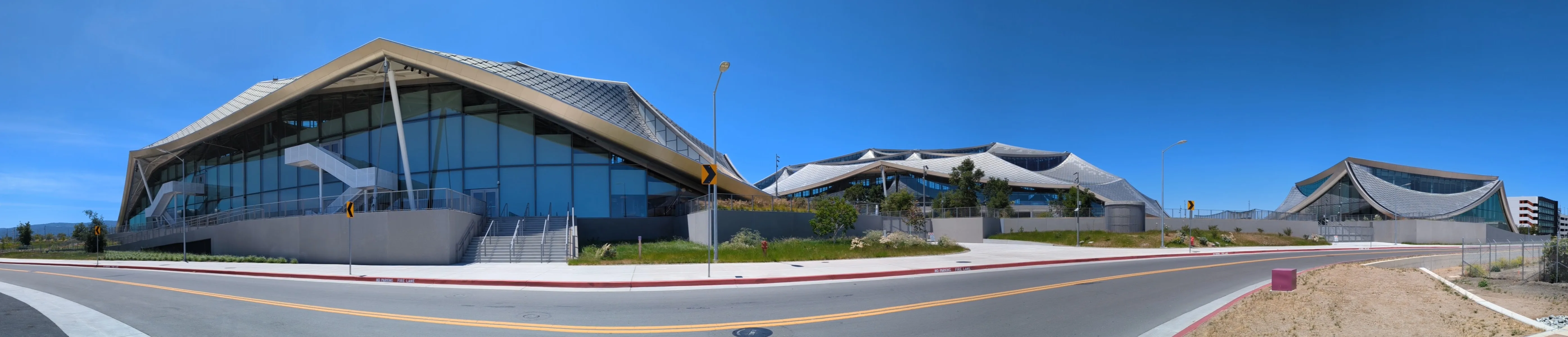 Google Bay View campus buildings with curved roofs beneath a blue sky