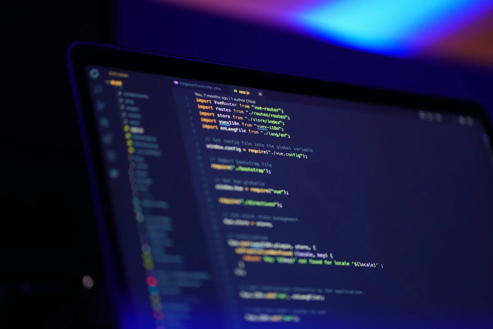 Laptop screen displaying code under blue and purple lighting