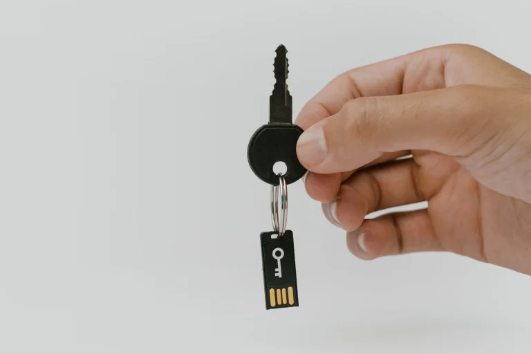 A hand holding a physical key and USB security key as an illustration of digital security