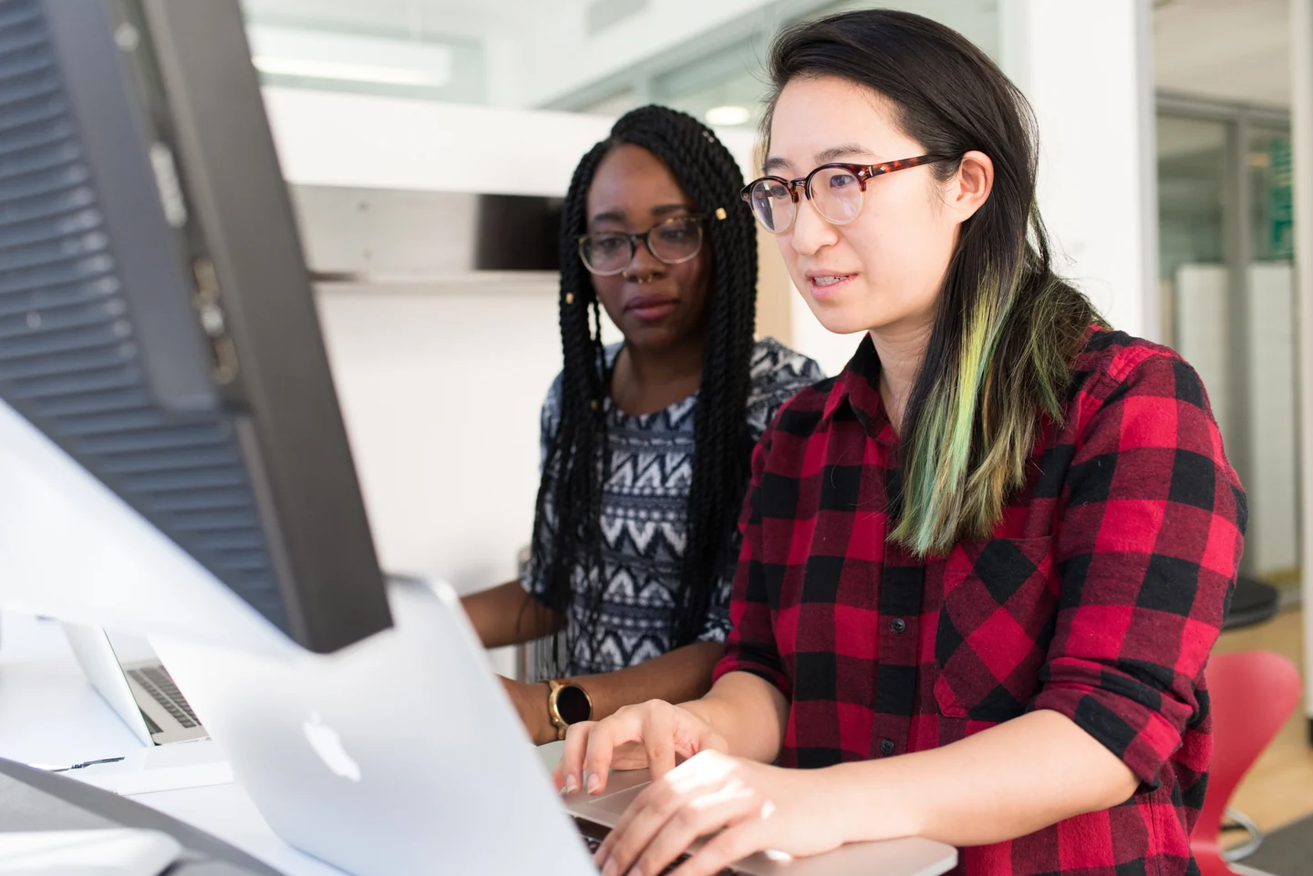 Two people working together at laptops in an office
