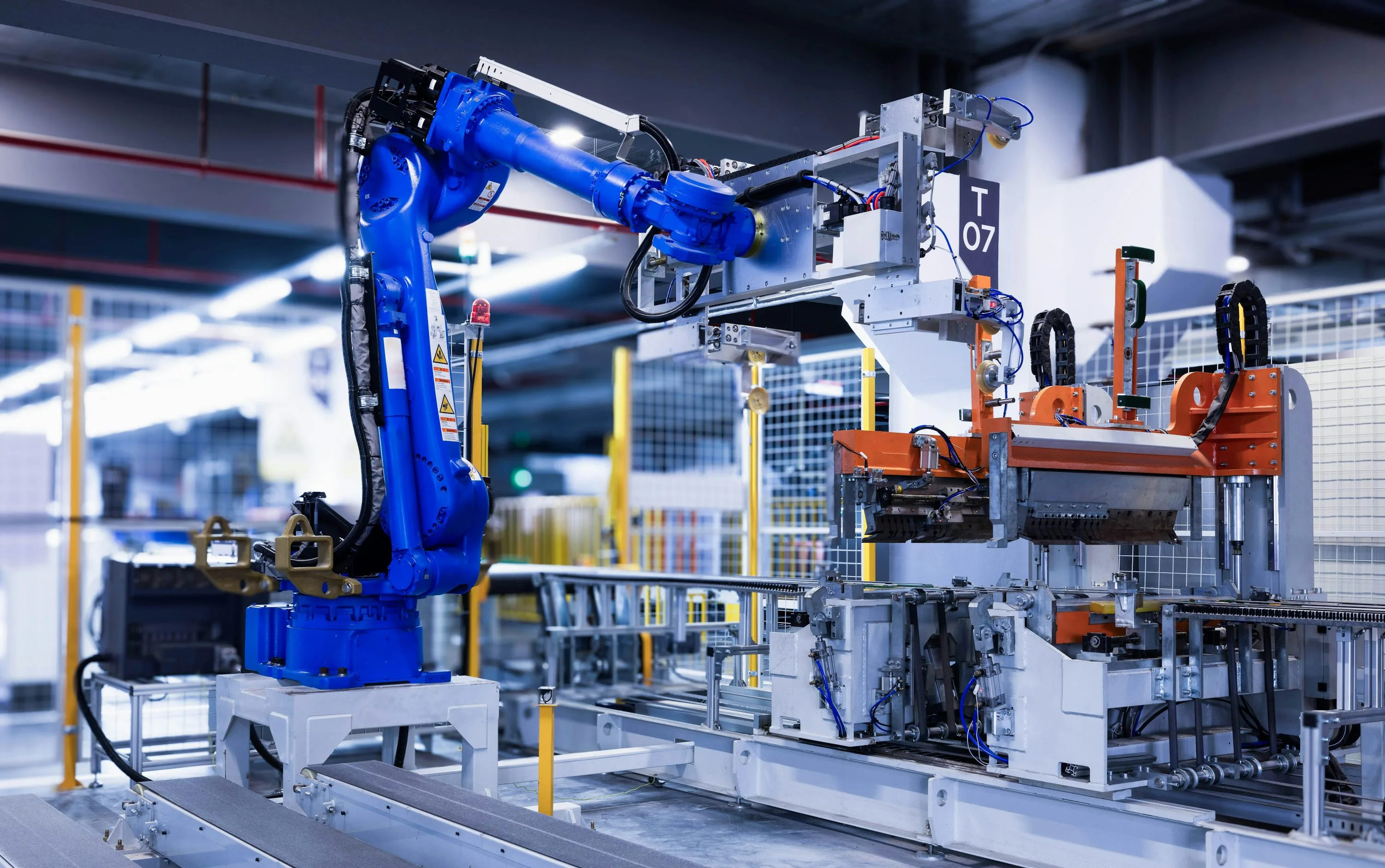 A blue industrial robot arm operating beside factory machinery