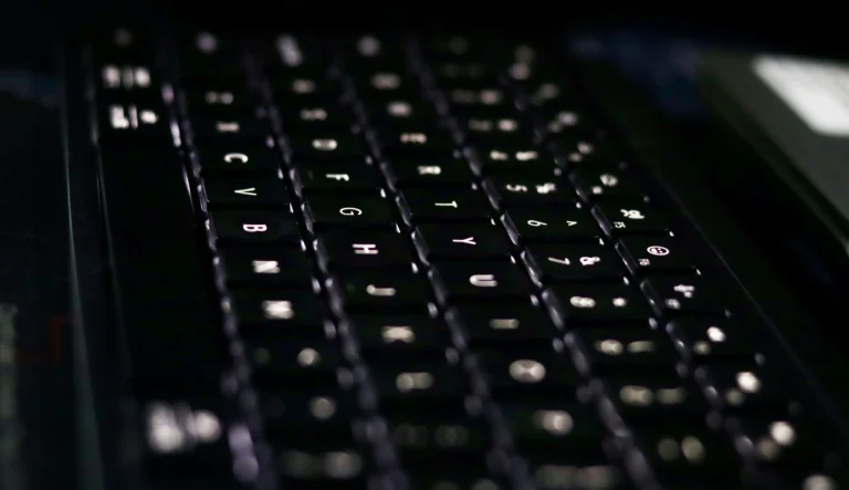 Close view of black computer keys with white backlighting and shallow depth of field