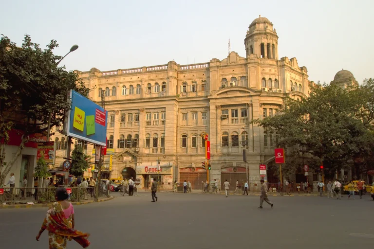 A billboard and street signs beside Park Mansions in Kolkata with pedestrians crossing the road