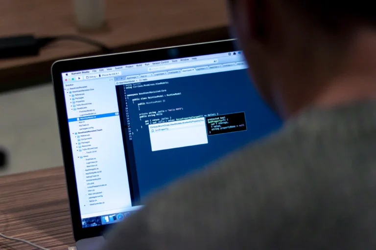 A laptop displaying a code editor viewed over a person’s shoulder