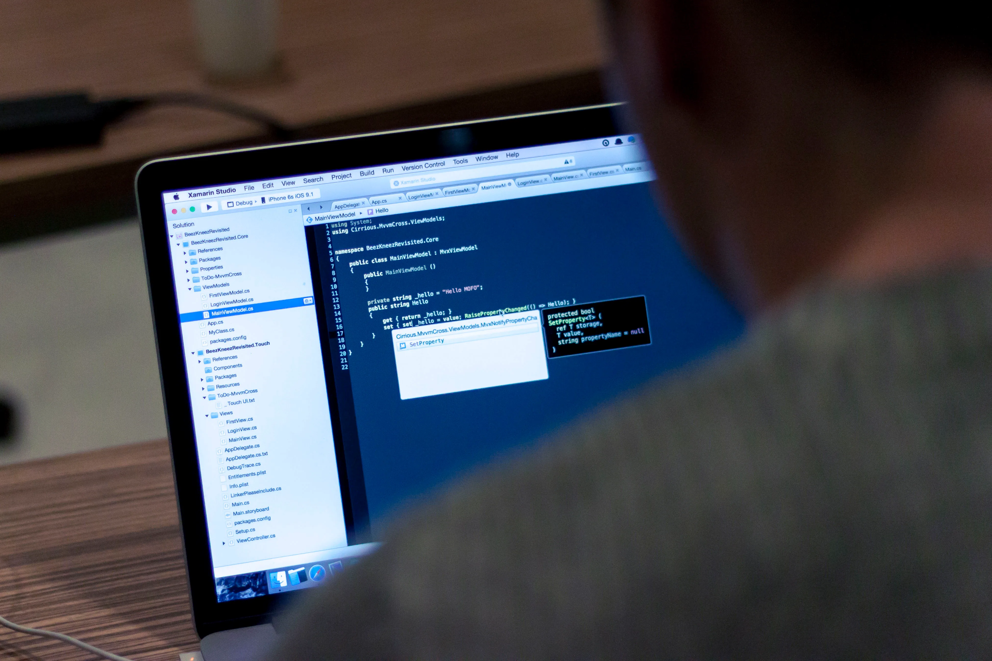 A laptop displaying a code editor viewed over a person’s shoulder