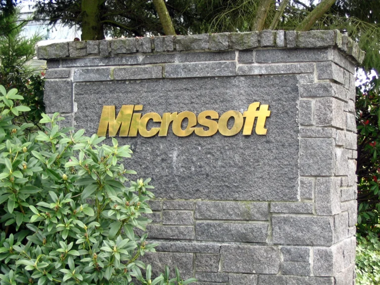 Gold Microsoft lettering on a stone sign surrounded by trees and shrubs