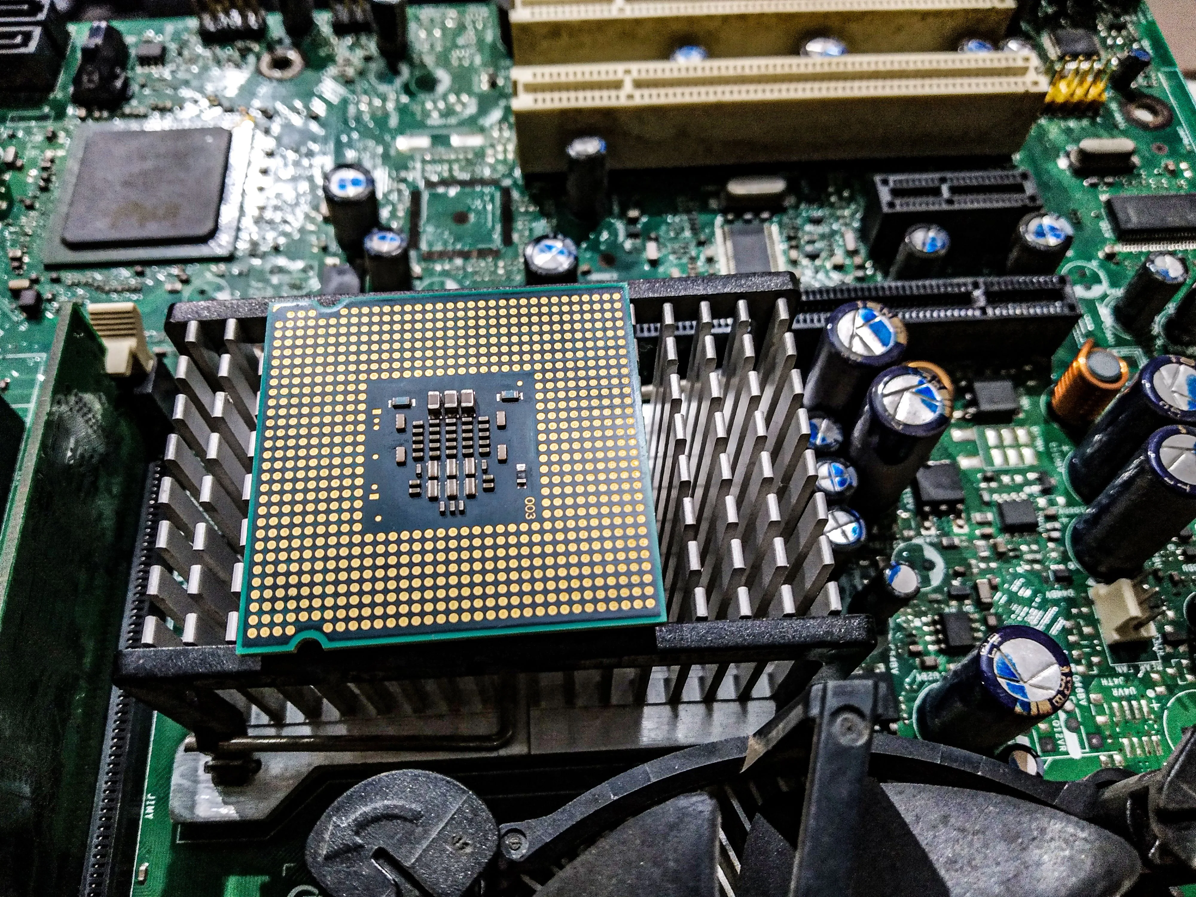 A processor rests on a heatsink above a green motherboard