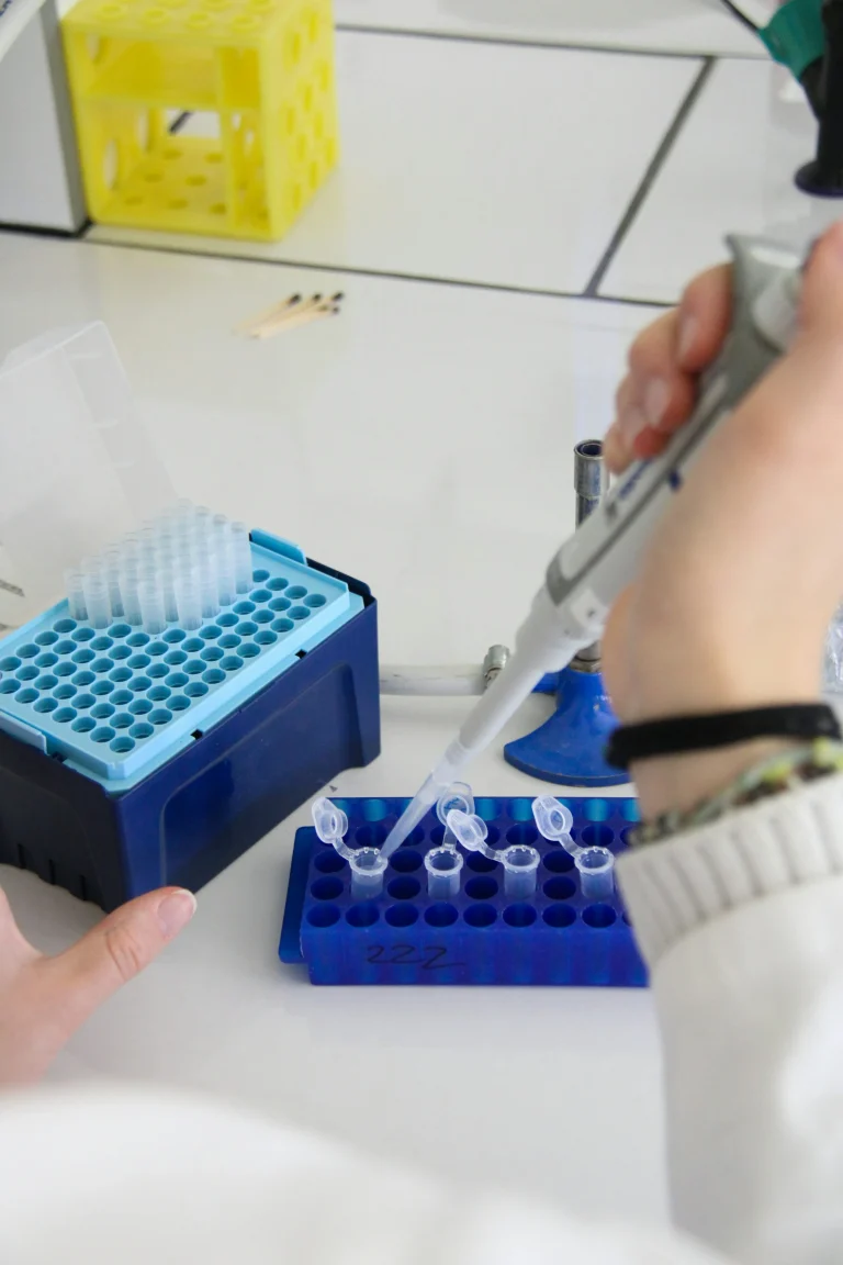 A technician holds a micropipette above small laboratory tubes