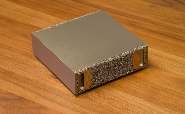 An earlier NVIDIA DGX Spark with a metallic enclosure and textured front panel on a wooden table