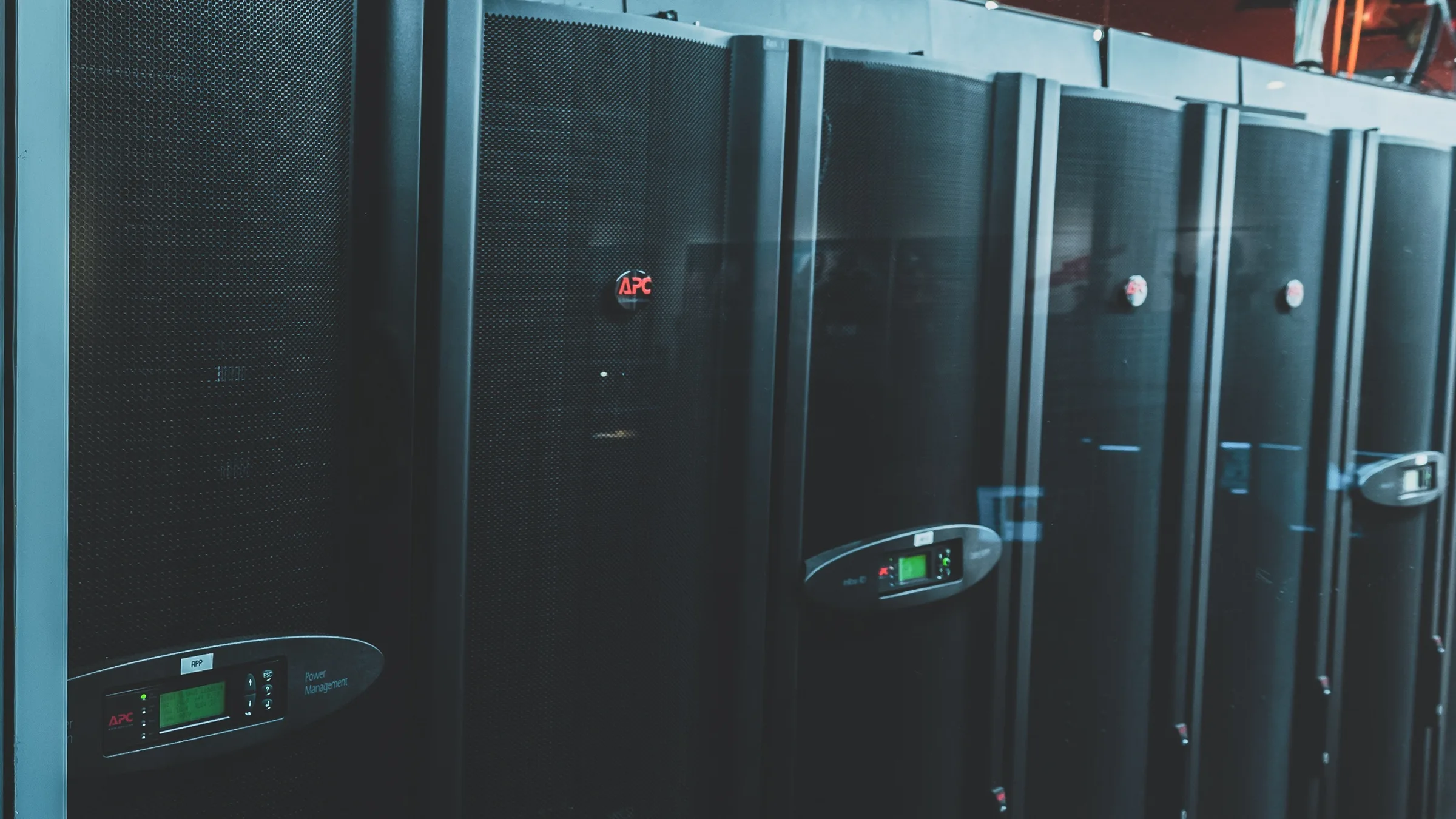 Black equipment cabinets with perforated doors and green power management displays seen through glass