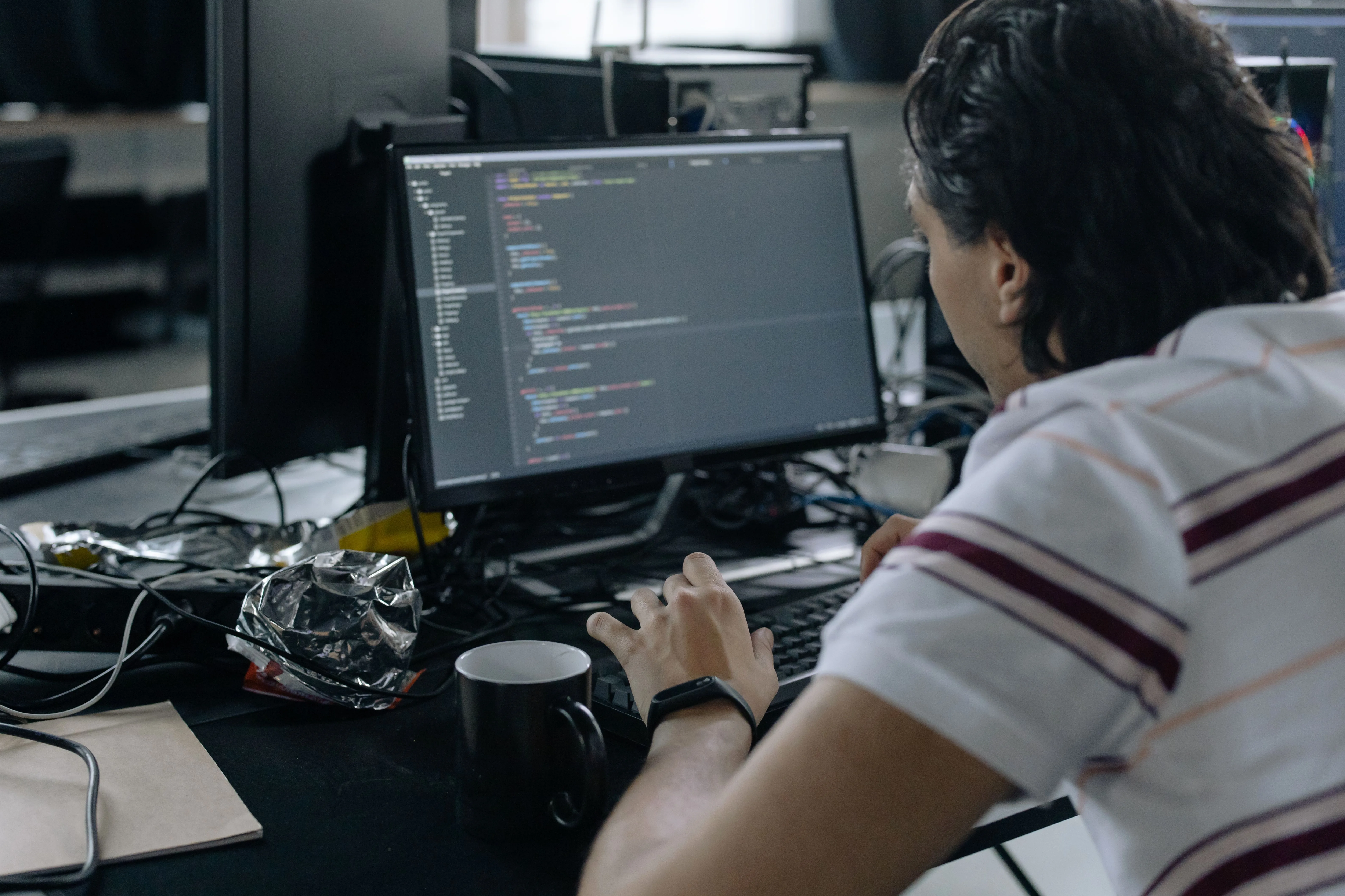 Person working at a desktop computer with code visible on the monitor