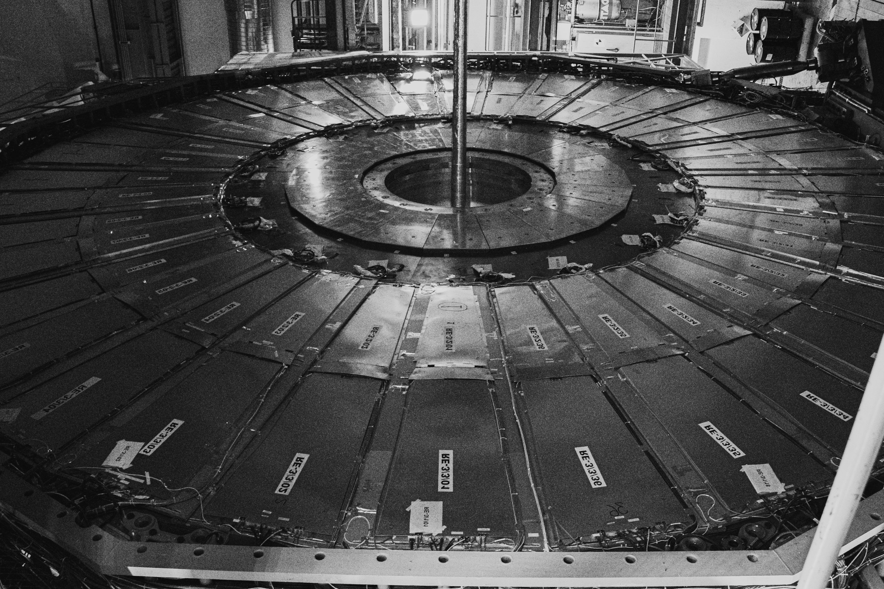 Black and white photograph of a circular CMS detector section at CERN with radial panels and a central opening