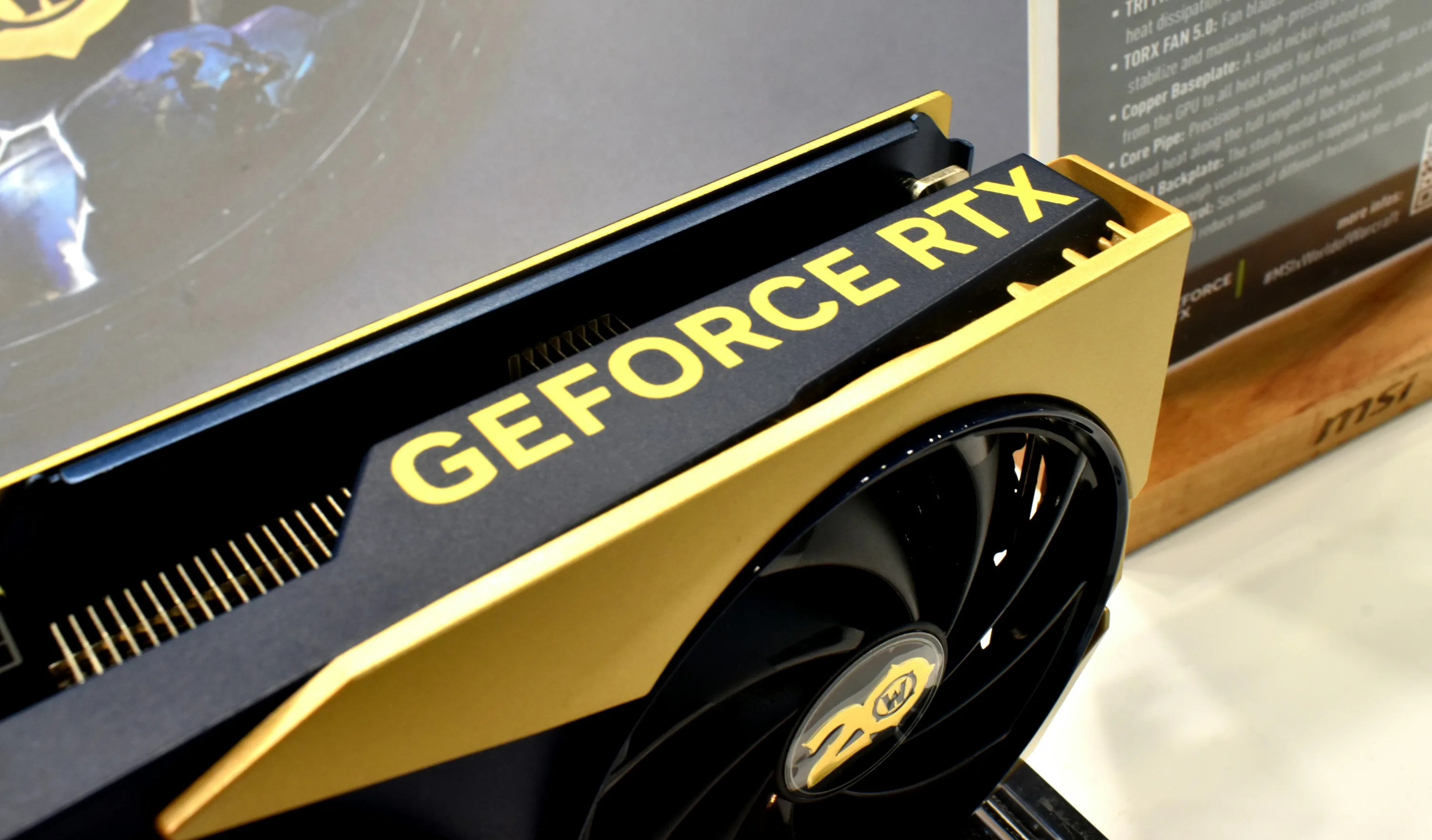 Close view of a black and gold GeForce RTX graphics card with its cooling fan