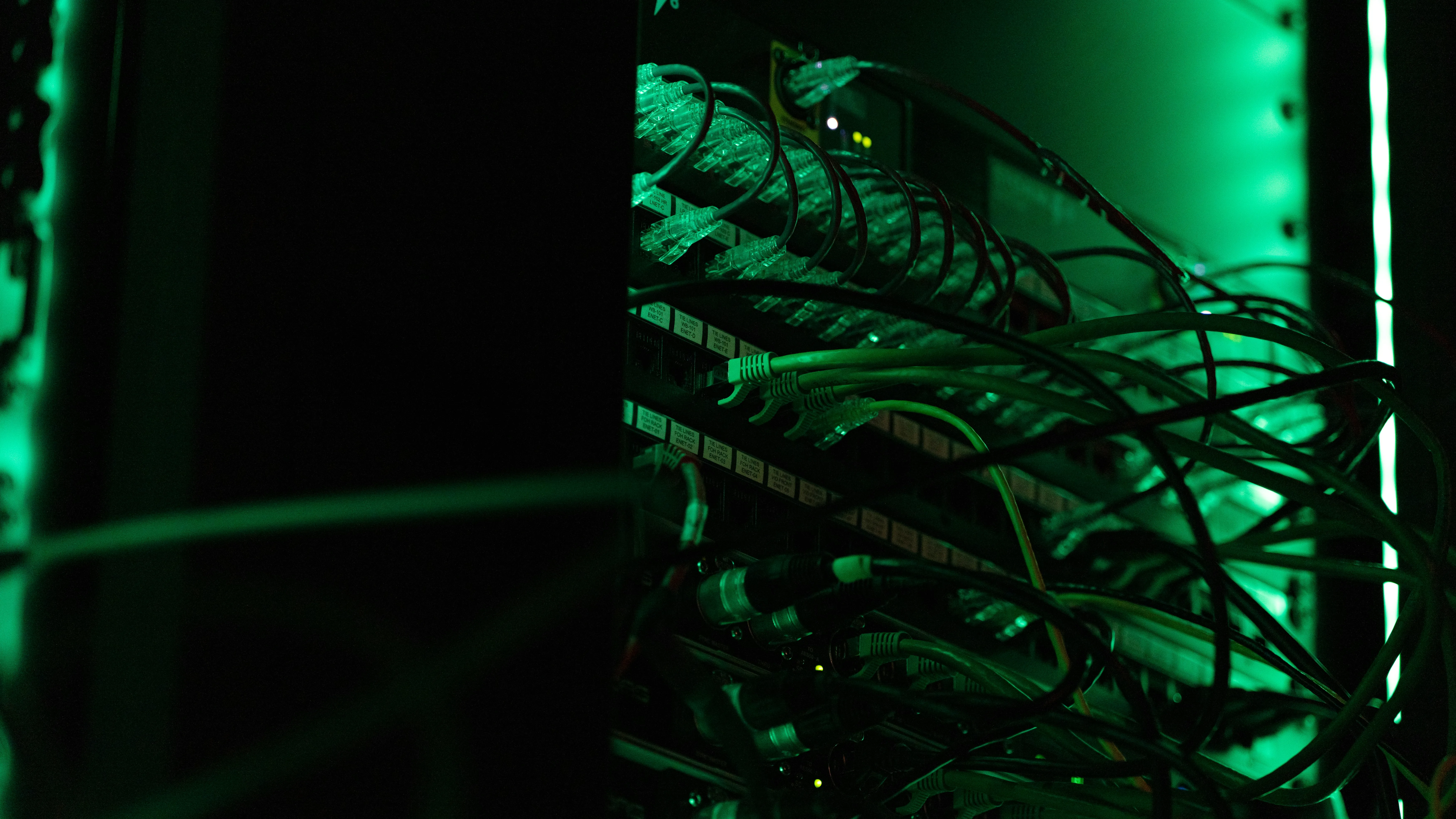 Rows of network ports and connected cables inside a rack under green lighting