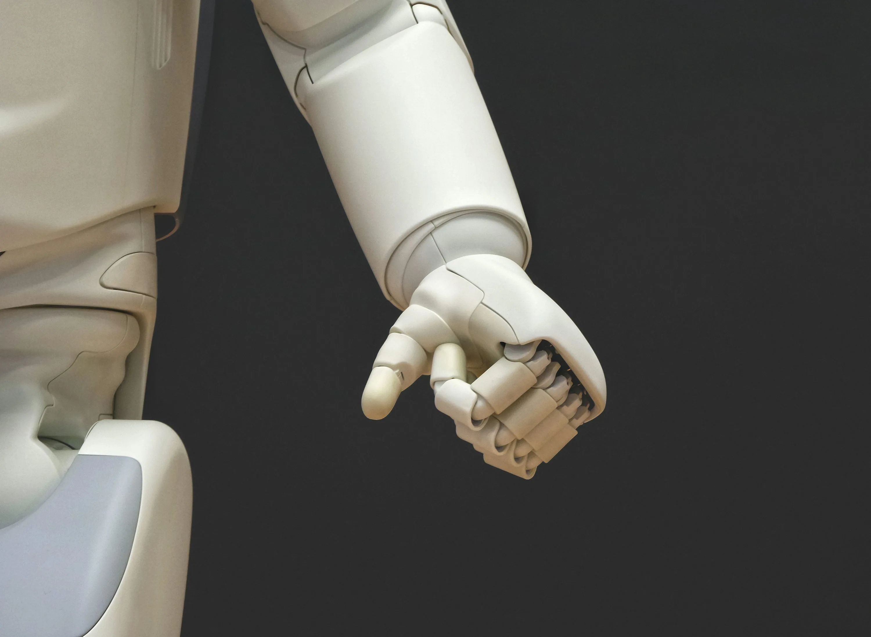 A white robot arm and articulated hand against a dark background