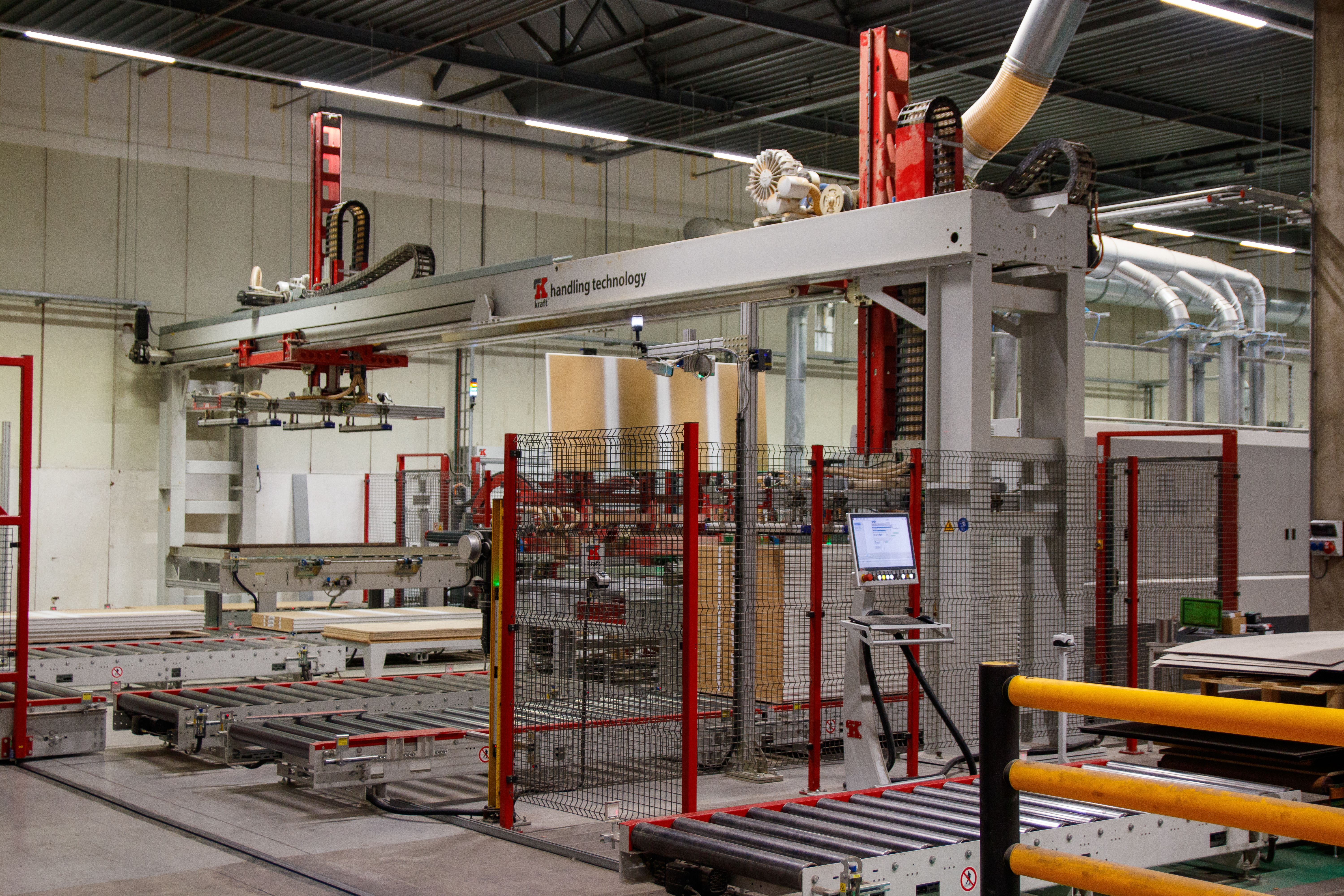 Factory conveyor rollers and handling machinery behind red and black safety fencing