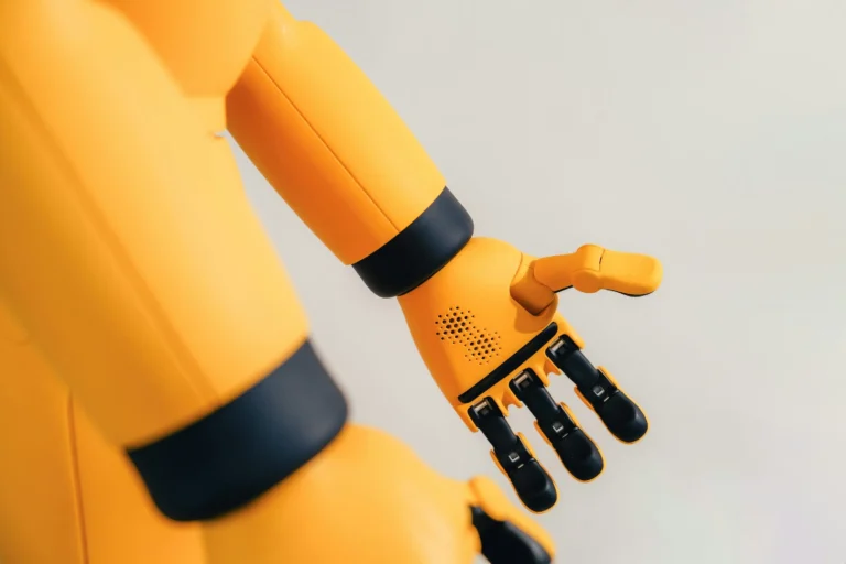 A yellow Mirokaï robot arm with black joints and articulated fingers