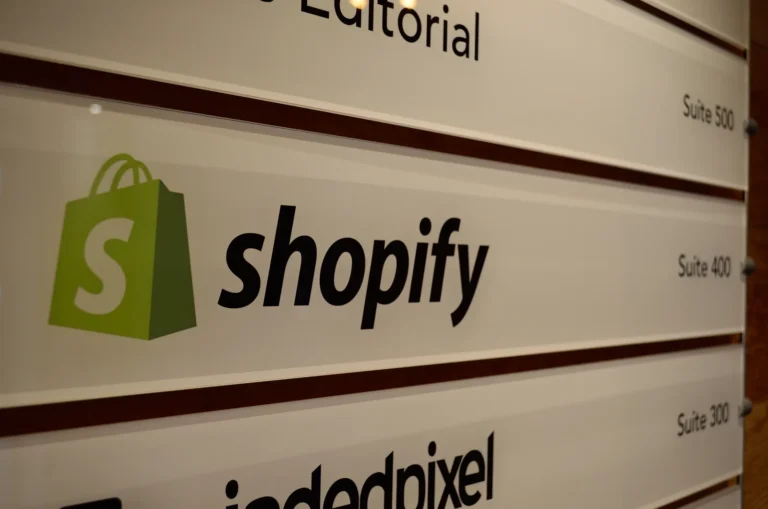 Green Shopify shopping bag logo and black company name on an office directory beside the label Suite 400