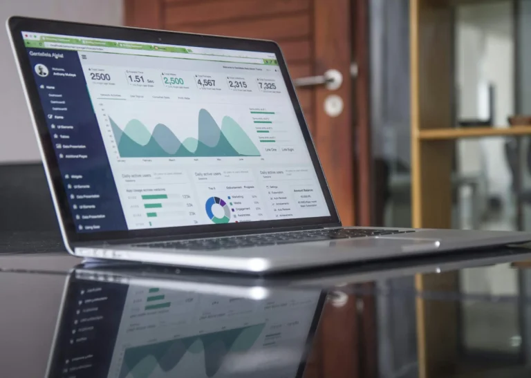 A laptop displaying charts and summary statistics on a glass table