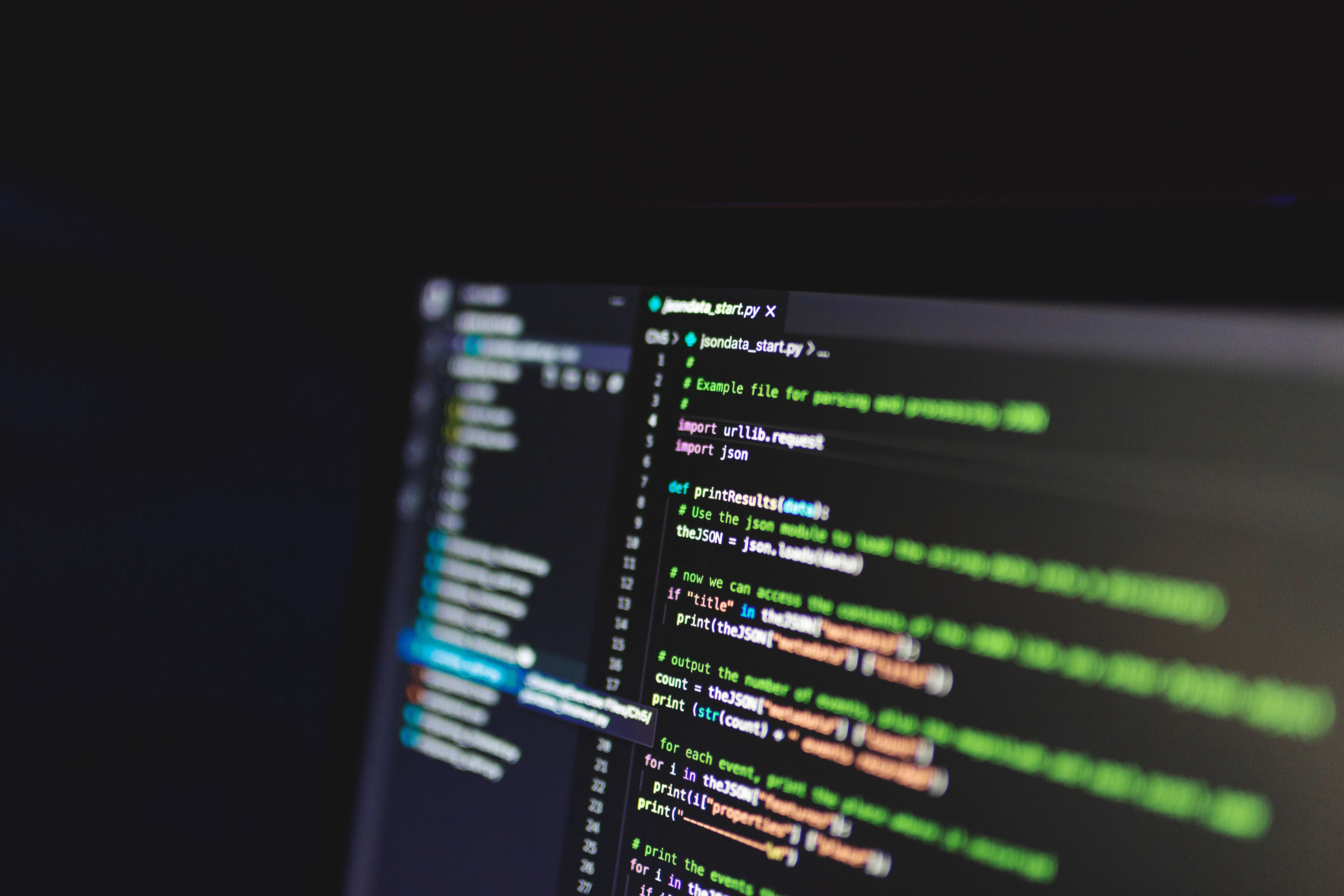 Python source code displayed on a computer monitor in a dark room.