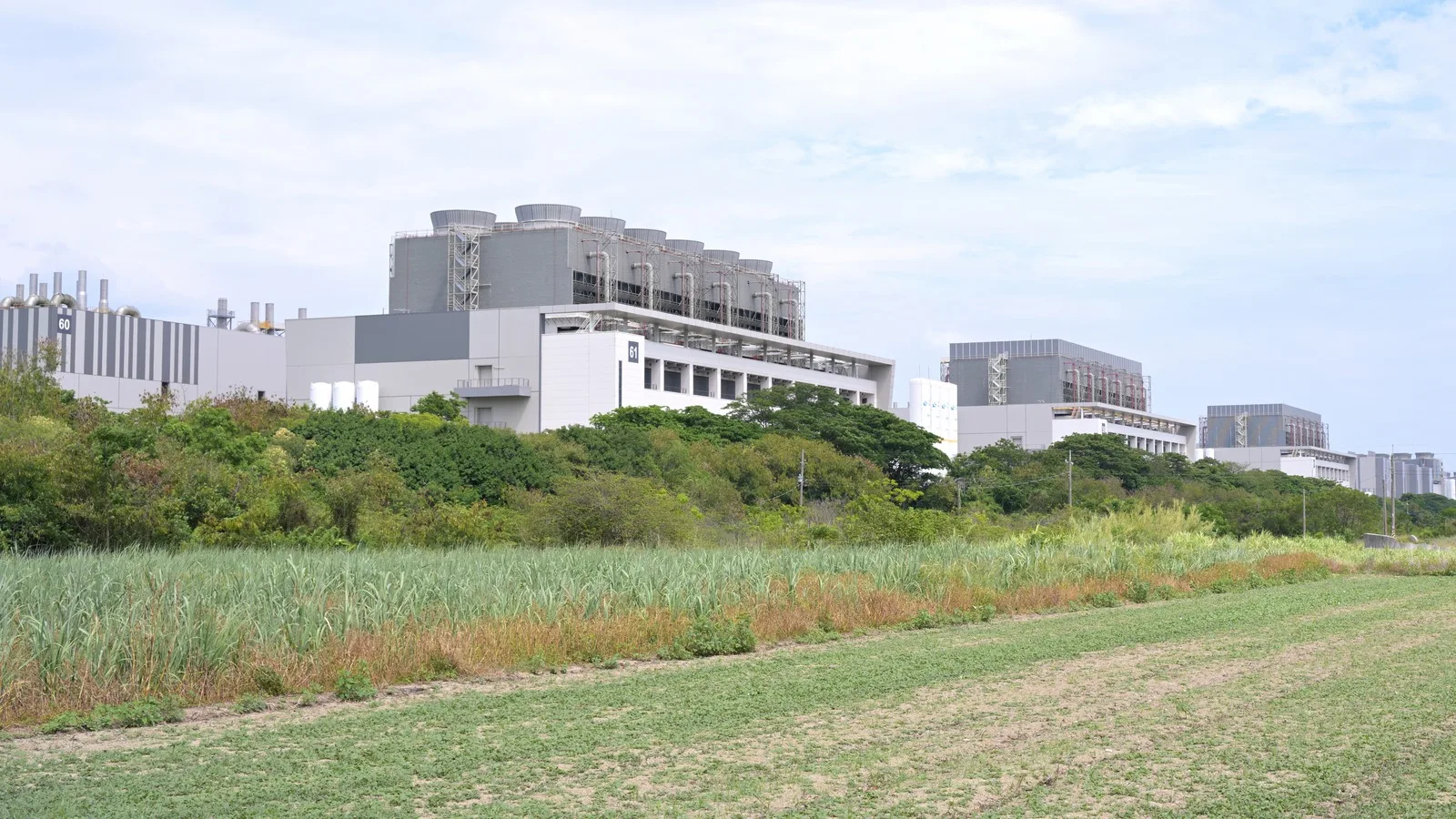 TSMC Fab 18 buildings and rooftop cooling equipment beyond green fields at Southern Taiwan Science Park.