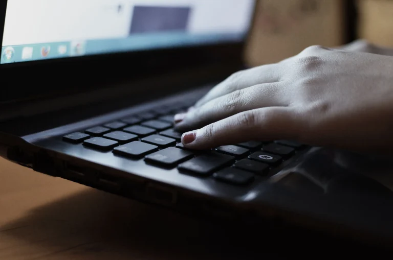 Hands typing on a black laptop keyboard