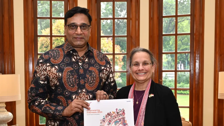 Indosat CEO Vikram Sinha and US Ambassador Kamala Shirin Lakhdhir holding an Indonesia development report in December 2024