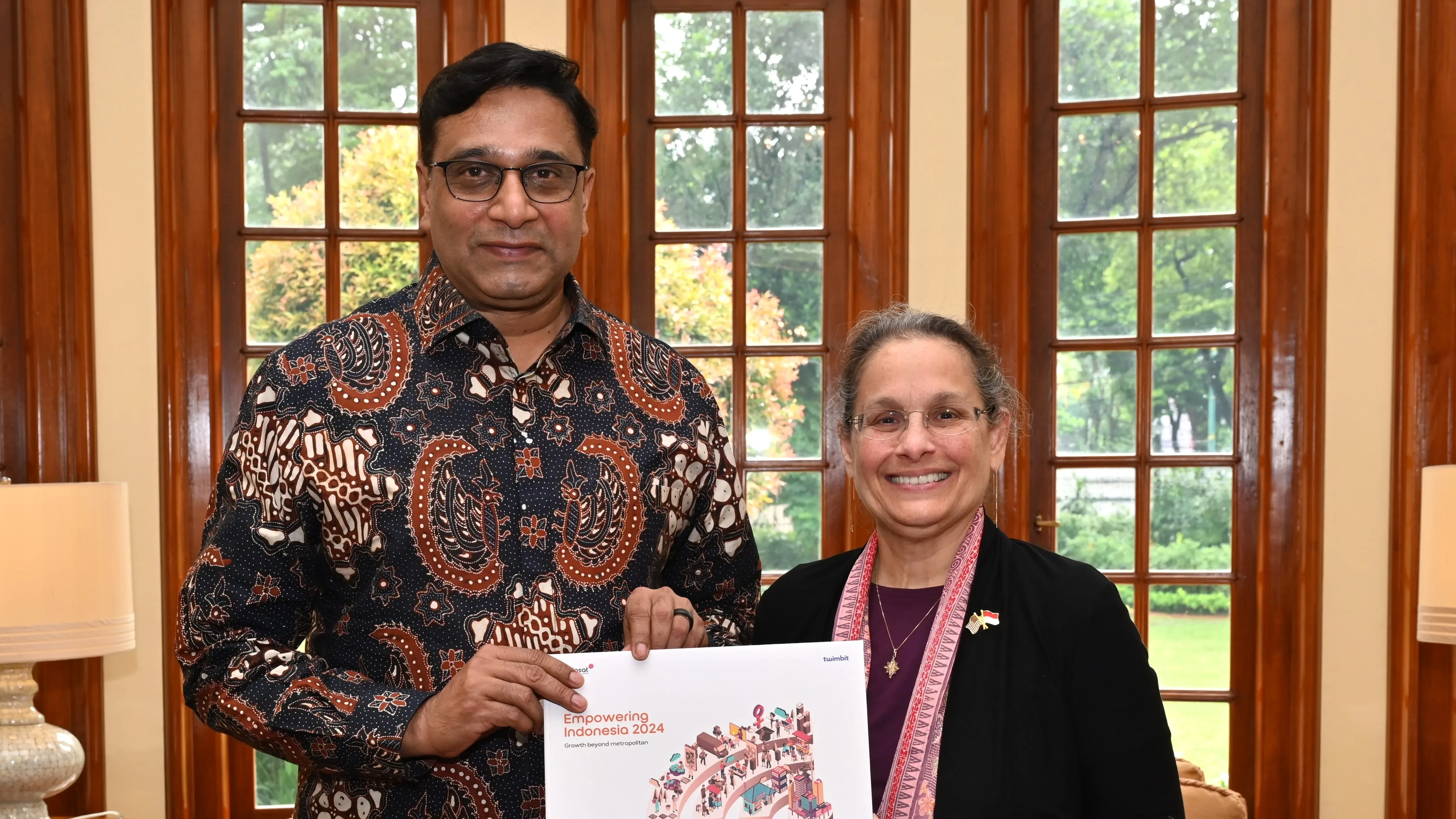 Indosat CEO Vikram Sinha and US Ambassador Kamala Shirin Lakhdhir holding an Indonesia development report in December 2024