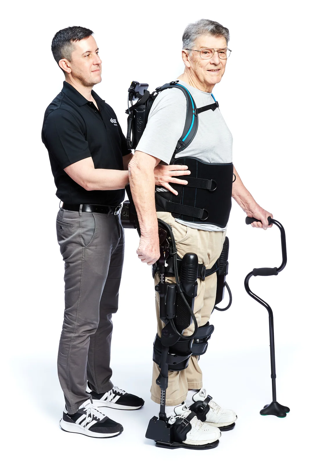 Person wearing an EksoNR exoskeleton beside a therapist against a white background